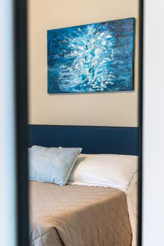 a bed in a room with a painting on the wall at Hotel Baia di Talamone in Talamone
