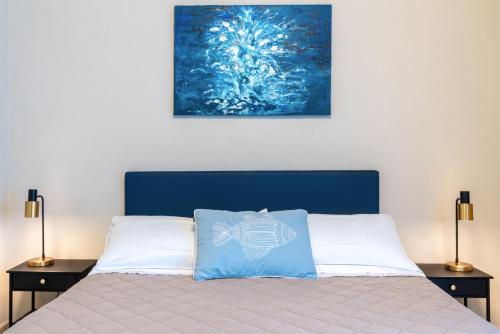 a bedroom with a bed with a blue headboard and two lamps at Hotel Baia di Talamone in Talamone