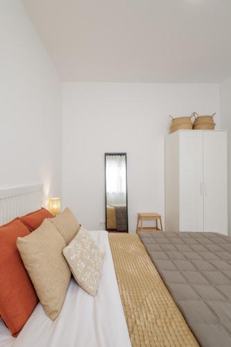 a white bedroom with a bed with orange pillows at Apartament a Sant Celoni, Montseny, Barcelona in San Celoni