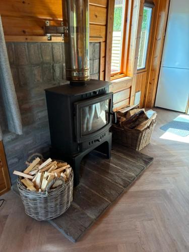 a stove in a room with two baskets of wood at Deveron Valley Cottages in Marnoch