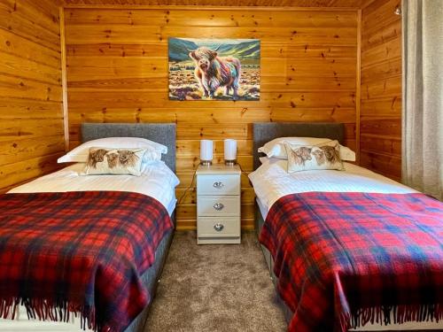 two beds in a room with wooden walls at Deveron Valley Cottages in Marnoch