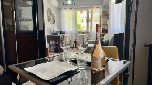 - une table en verre avec une bouteille de vin et des verres dans l'établissement Confort Moderne au Cœur d'Antibes, à Antibes