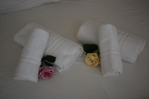 two rolls of towels with flowers on a bed at CapeVerde in Glóssa