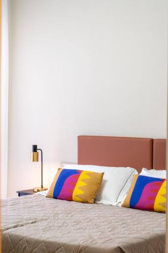 a bedroom with a bed with colorful pillows on it at Hotel Baia di Talamone in Talamone