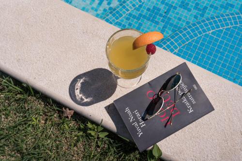 a book and a glass of orange juice next to a pool at Vila Agava, Konavle in Gruda