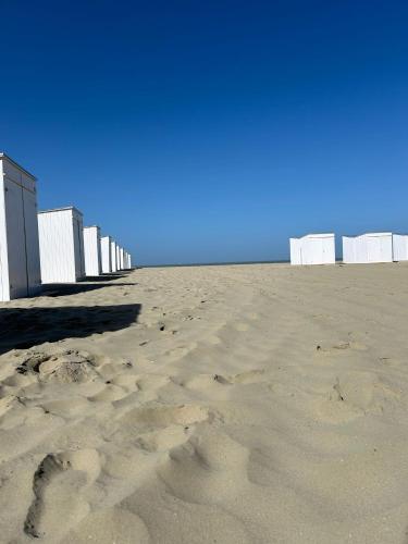 a sandy beach with a row of white beach huts at Suite Felice in Knokke-Heist