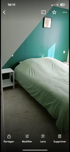 un lit dans une chambre avec un mur bleu dans l'établissement Gîte ALRA 3 chambres, à Manneville-ès-Plains