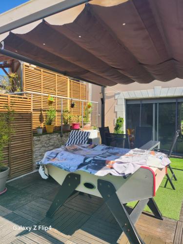 a bed sitting under an umbrella on a deck at les oliviers in Veigné