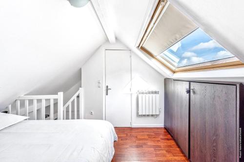 une chambre avec un lit et une lucarne dans l'établissement Gaité - Comfort & Convenience Montparnasse 1bdr, à Paris