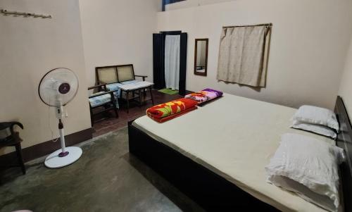 a bedroom with a large white bed with a fan at K J Homestay in Cherrapunji