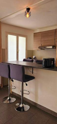 une cuisine avec un comptoir et deux tabourets de bar dans l'établissement T2 Dernier Étage avec Terrasse 5 min de la Mer, à Nice
