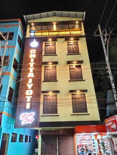 a building with a neon sign in front of it at Chitta Jyoti Home Stay in Silchar