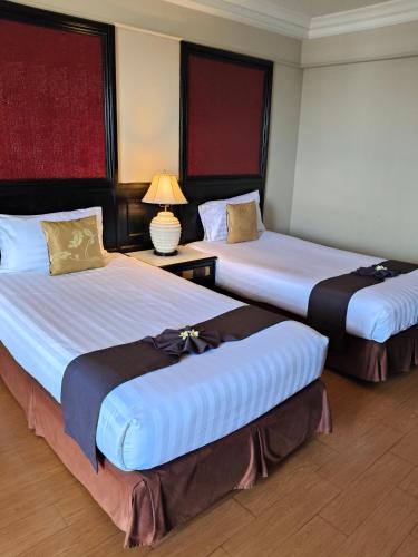 a hotel room with two beds and a lamp at First Pacific Cirrus in Pattaya Central