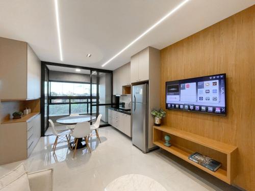 a kitchen with a table and a tv on a wall at Studio Vista Dourada in Campo Grande