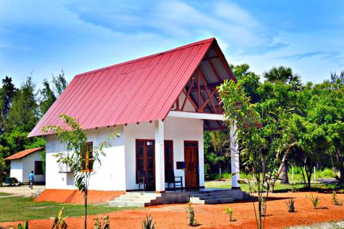 a small white house with a red roof at Coral Waves Inn Pasikuda in Kalkudah