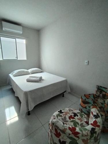 a white bedroom with a bed and a chair at Casa Sossego in Marechal Deodoro