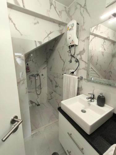 a white bathroom with a sink and a shower at Villa Supranee Paradise in Câmara de Lobos