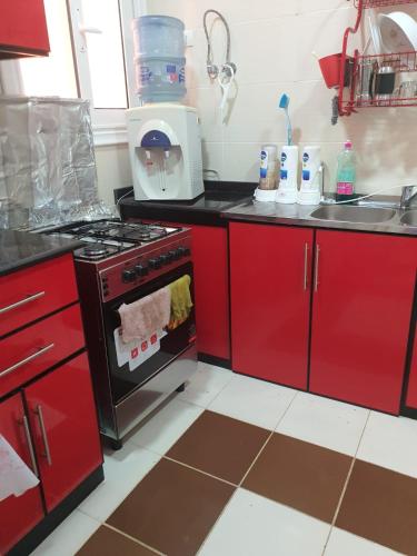 a kitchen with red cabinets and an oven at Koun Ras ElHikma كون راس الحكمة in Ras Elhekma