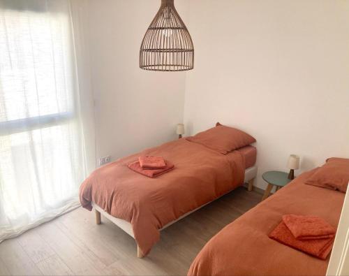 une chambre avec deux lits avec des draps orange et une cage à oiseaux dans l'établissement New house 10 min from the beach, à Lit-et-Mixe