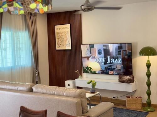 a living room with a couch and a flat screen tv at ChiangMai RedDoor Pool Villa in Chiang Mai