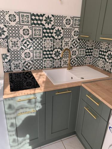 - une cuisine avec un évier et un mur en carrelage dans l'établissement Jolie studio meublé tout équipé, à Châlons-en-Champagne