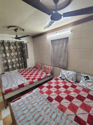 a room with two beds and a ceiling fan at hotel shiv in Dwarka