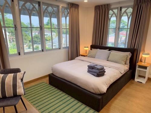 a bedroom with a large bed with windows at ChiangMai RedDoor Pool Villa in Chiang Mai