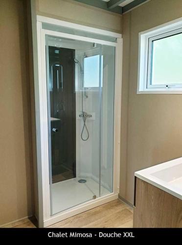 une douche en verre dans une salle de bain avec un lavabo dans l'établissement Locations au camping Les Pialades, à Nabirat