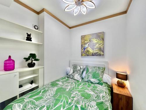 - une chambre avec un lit vert et un ventilateur de plafond dans l'établissement Superbe appartement face à la mer, à Roquebrune-Cap-Martin
