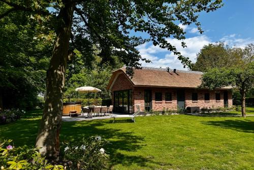 a brick house with a table and chairs in a yard at Landhuisje ter Heide - charming cottage with hottub in De Moer