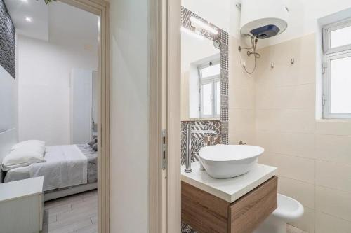 Un baño con lavabo, espejo y cama. en Dafne home, en Siracusa