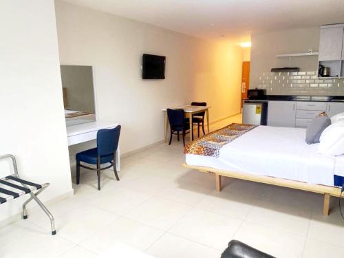 a bedroom with a bed and a kitchen and a table at Résidences Les Hauts de l'Indenié in Abidjan
