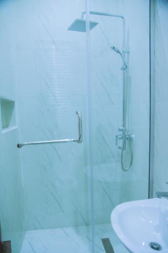 una ducha con una puerta de cristal junto a un lavabo en Cozy 4BDR Home with Snooker, 15mins from Airport, en Hausa