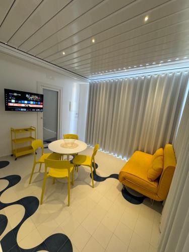 Una sala de estar con una mesa y sillas y un televisor. en Soleonde, en Marina di Ragusa