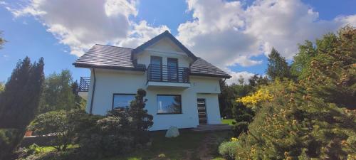 a small white house on a hill with trees at Sulidom in Sulistrowice