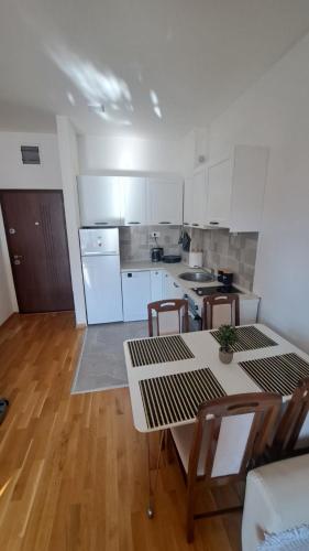 a kitchen with white cabinets and a table and chairs at Blue wave apartman in Becici