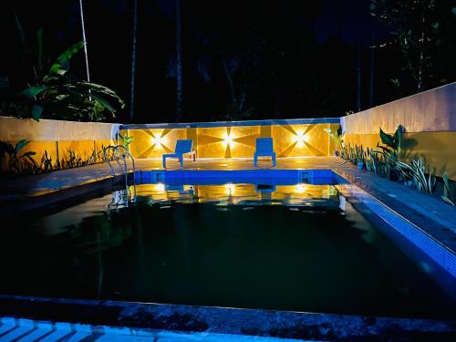 a swimming pool at night with chairs and lights at Swargam Pool Resort in Varkala