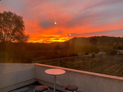 a sunset from a balcony with a table and stools at Location Vinon-sur-Verdon in Vinon-sur-Verdon