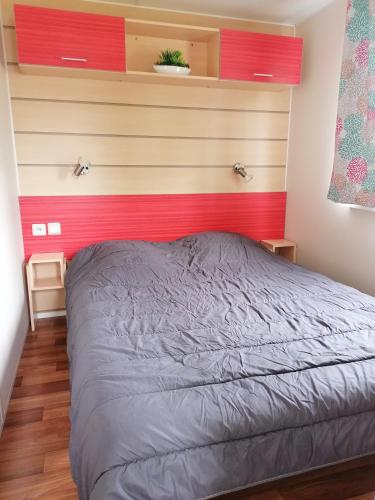 Ce lit se trouve dans une chambre dotée d'un mur rouge. dans l'établissement Mobile home 12 lac de bairon, à Sauville