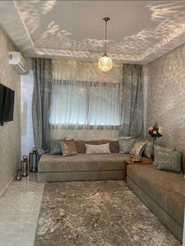 a living room with a large couch in front of a window at Appartement avec piscine à El Mansouria in Pont Blondin