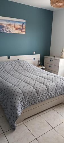 Una cama en un dormitorio con una pared azul. en La marine, en Le Crotoy