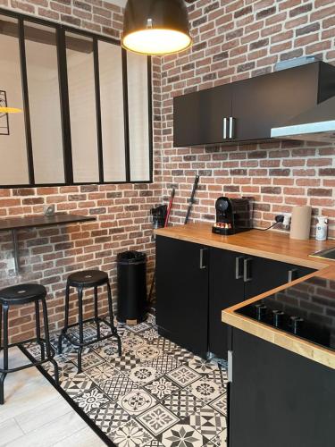 une cuisine avec des armoires noires et un mur en briques dans l'établissement Superbe studio au pied de notre dame de la garde, à Marseille