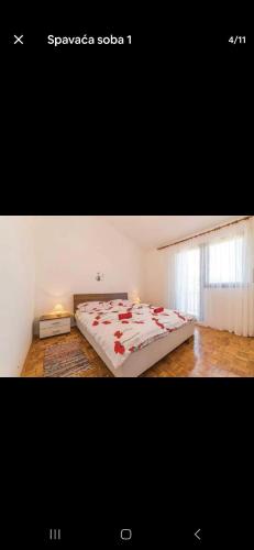 a bedroom with a bed with red flowers on it at Apartman Alar in Pridraga
