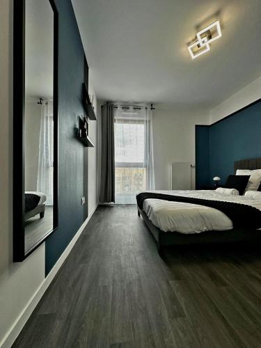 une chambre avec un lit et un mur bleu dans l'établissement Appartement T2, à Pierrefitte-sur-Seine