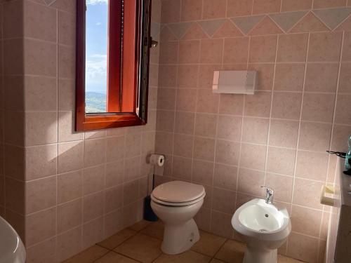 a bathroom with a toilet and a sink and a window at Casa San Pasquale, windsurf e natura, panorama mozzafiato in San Pasquale