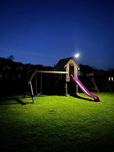 a playground with a slide in the grass at night at Zielona Dolina Hoczew in Hoczew