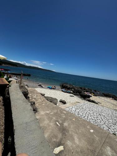 a beach with people laying on the sand and the water at Krk Houses in Kornić