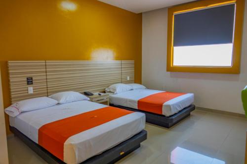 two beds in a room with orange and white at Hotel Motel Nivel 10 in Manzanillo