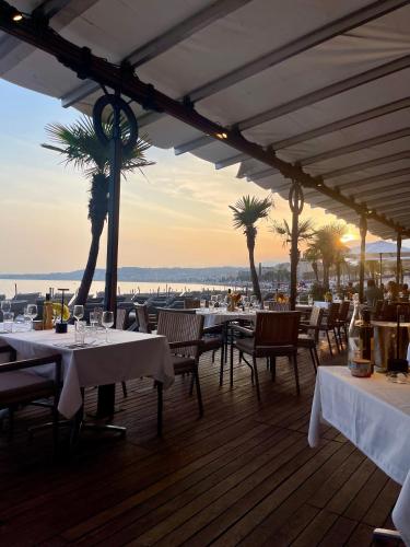 un restaurant avec des tables blanches, des chaises et des palmiers dans l'établissement Nouveau appartement carré d'or, à Nice