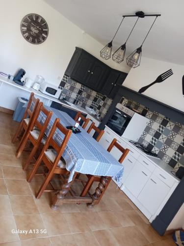 une table et des chaises dans une cuisine avec une horloge murale dans l'établissement Chez Nadette, à Saint-Vincent-de-Cosse